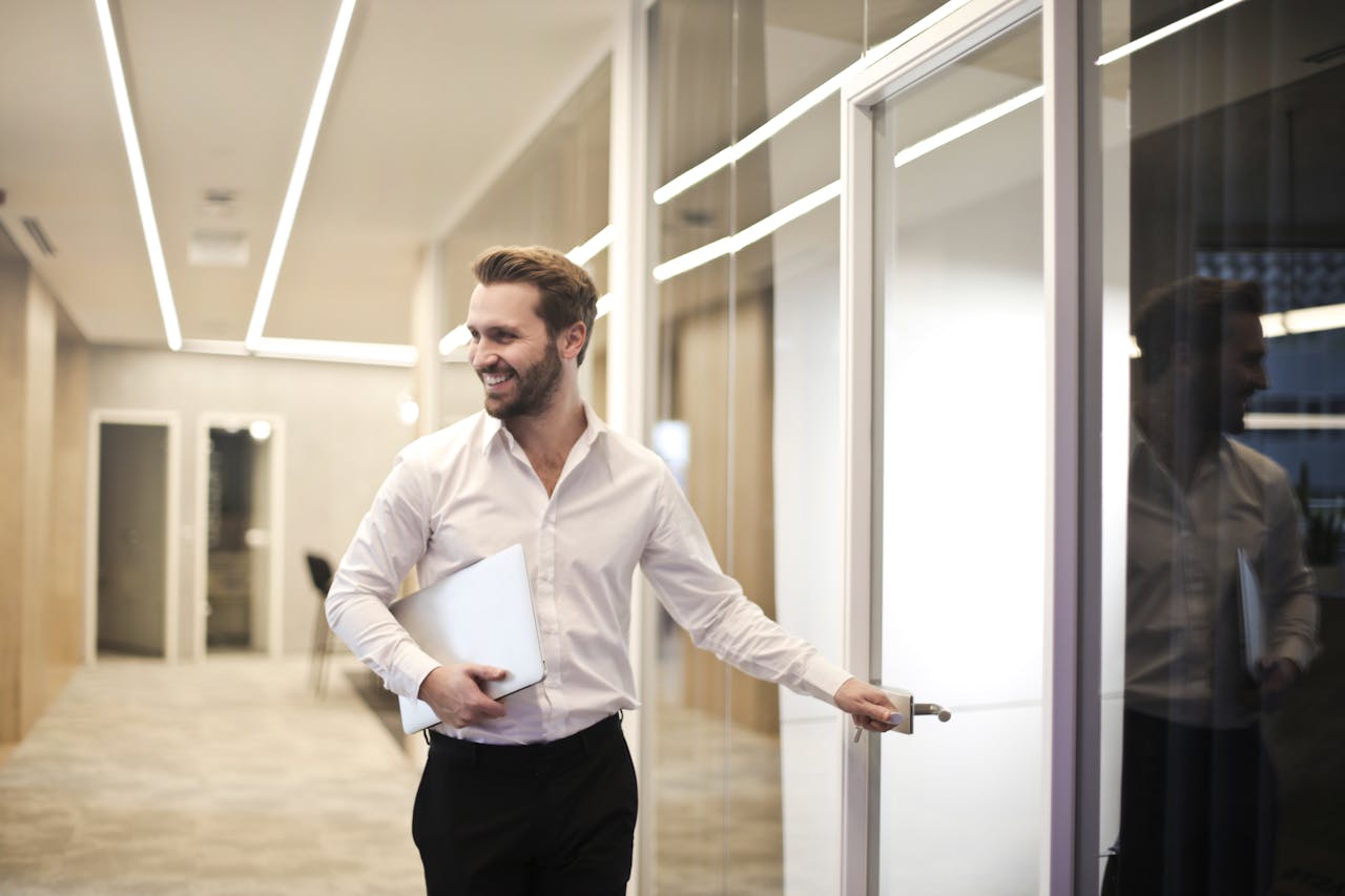Man walking into office while holding laptop
